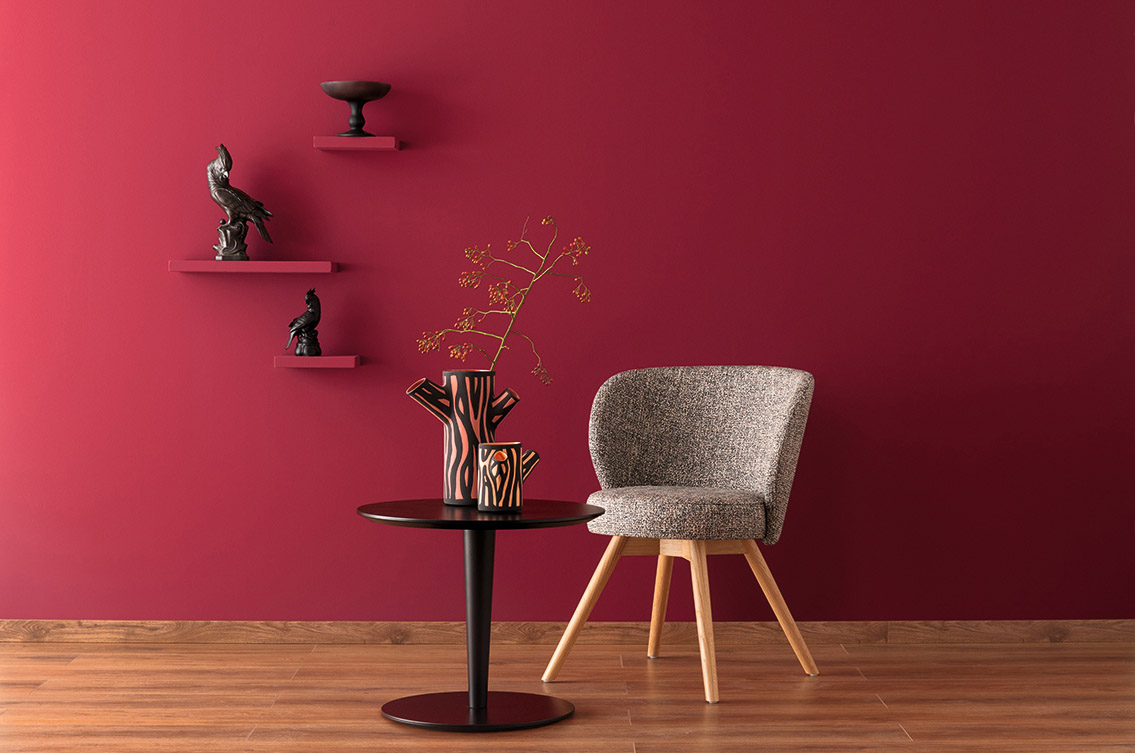 Sessel und kleiner Tisch im Wohnzimmer und Wand in Designfarbe Gefühlvolles Herzensrot