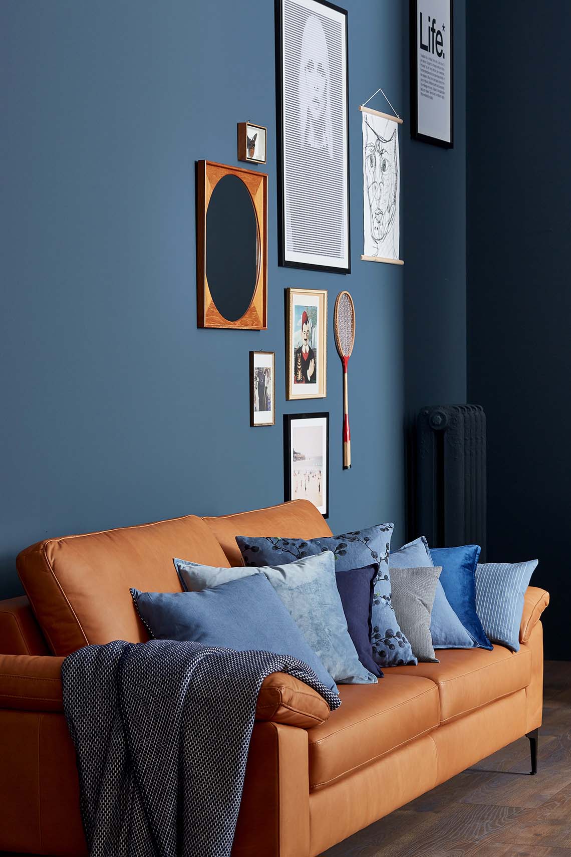 Wohnzimmer mit braunem Sofa und blauen Kissen, Trendfarbe Blueberry